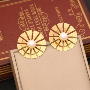 Golden sunburst pearl earrings displayed on a beige jewelry box with vintage book