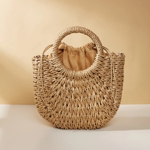 Detail of hand-woven half-moon straw bag featuring a round handle and beige drawstring lining