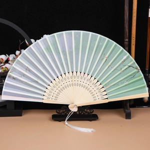 Detail of green floral fabric fan with ornate bamboo ribs and white silk tassel