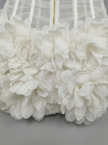 Close-up of white mesh dress featuring 3D floral petals and a gold metal zipper detail