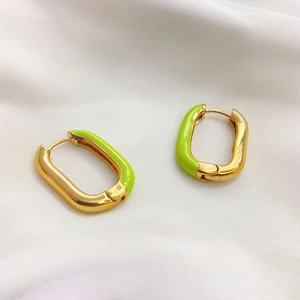 Detail view of gold and neon green enamel hoops on white silk fabric background