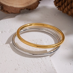 Minimalist round stainless steel bangles in 18K gold and silver finishes on stone