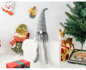 Detail of a Christmas gnome with grey knit hat and striped long legs on a white stand