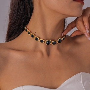 Close-up of vintage resin necklace with gold-tone metal circles and black cabochon gems