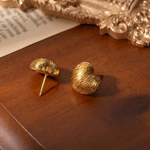 French style heart-shaped gold studs in brushed titanium steel on vintage background