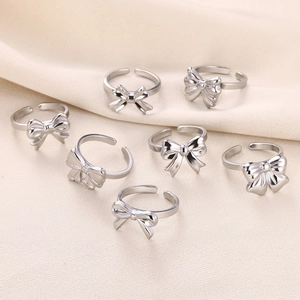 Minimalist silver bow rings with adjustable open design on elegant beige fabric