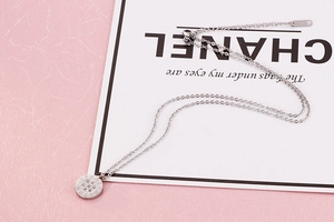 Detail of silver titanium steel necklace with Roman numeral pendant and pavé zircons