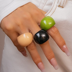 Close-up of vibrant resin rings in black, pastel pink and green worn by a fashion model