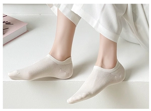 Beige cotton low-cut liner socks on model feet with back heel tab for anti-slip comfort