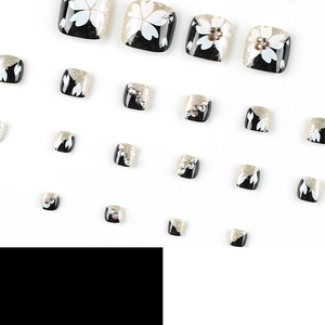 Short French press-on toe nails with black base, white flowers, gold glitter and rhinestones