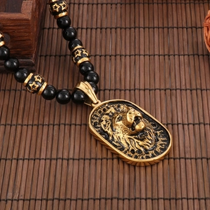 Detail of golden lion head pendant on black and gold beaded necklace over bamboo mat