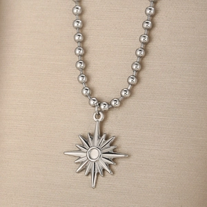 Gros plan d'un collier chaîne à billes en acier argenté avec pendentif étoile solaire