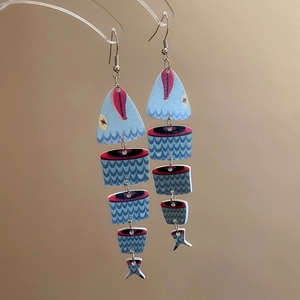 Close-up of ethnic fishbone pendant earrings with artistic prints and metal hooks