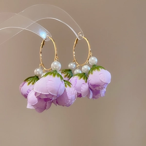Detailed view of floral dangle earrings with purple fabric petals and white pearls