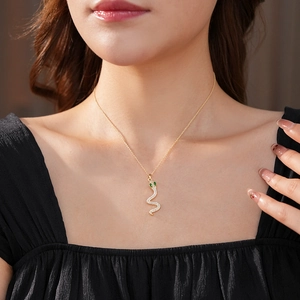 Dettaglio della collana a serpente dorata con zirconi e occhi di pietre verdi sulla modella