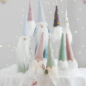 Nordic Christmas gnomes with sequined hats and white beards on lace surface with bokeh lights