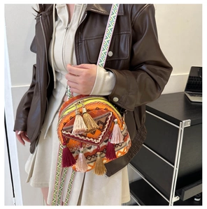 Ethnic style round crossbody bag featuring colorful tassels and geometric patterned strap
