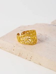 Detailed close-up of hollow gold-plated titanium steel ring on a textured stone base