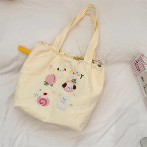 Detail of cute puppy embroidery and drawstring closure on a soft yellow canvas tote bag
