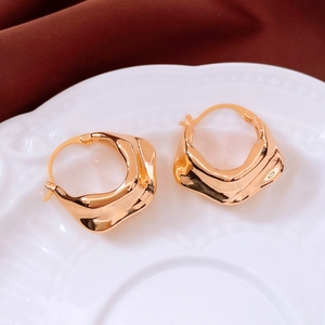 Detail shot of 18K gold plated earrings with irregular liquid metal texture on ceramic