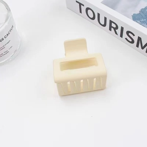 Detail of matte cream rectangular hair claw clip with lifestyle props on white background