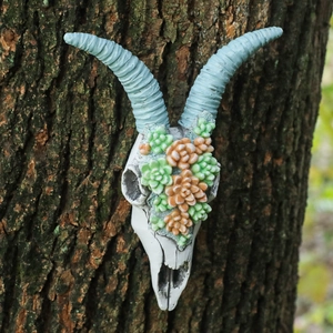 Vintage resin cow skull wall decor with blue spiral horns and colorful succulents