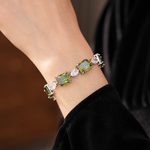 Macro detail of silver bracelet featuring square emerald gemstones and sparkling zircon