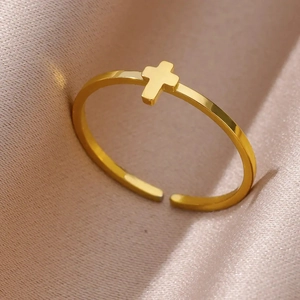 Macro close-up of gold-plated stainless steel cross ring on pink silk background