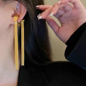 Detail of long gold snake chain tassel ear cuff on model with elegant metal finish