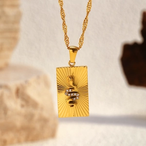 Detail of 18k gold sunburst pendant with crystal-encrusted snake on water wave chain