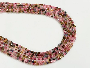 Détail macro de perles de tourmaline facettées multicolores en courbe sur fond blanc