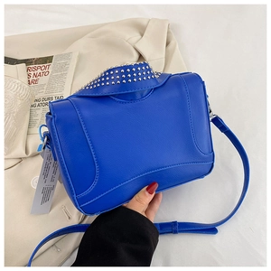Detailed view of blue punk rivets and shirt collar design on the textured crossbody bag