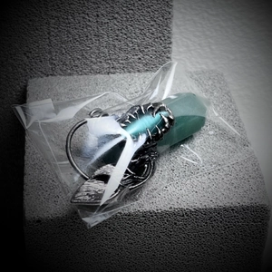 Detailed view of silver dragon claw holding a green hexagonal stone pendant for Halloween