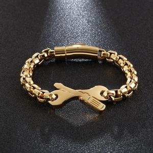 Detail of gold-tone wrench and screwdriver charms on a heavy metal chain bracelet