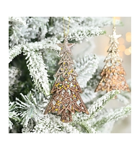 Detail of glittery bronze Christmas tree ornament hanging on a snowy pine branch