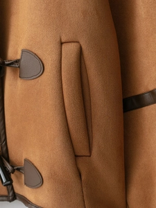 Detail of suede texture with leather trim and stitching on brown shearling coat
