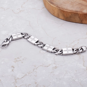 Détail d'un bracelet à maillons avec croix incrustées de strass sur fond de marbre