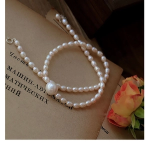Close-up of white baroque freshwater pearl necklace on vintage book with orange flower