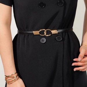 Detail of elegant black skinny belt with gold interlocking circular metal buckle on dress