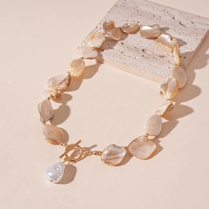 Detail of champagne shell beads and white baroque pearl pendant with golden OT clasp