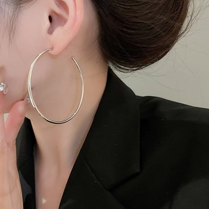 Close-up of a model wearing large polished silver hoop earrings with a black blazer