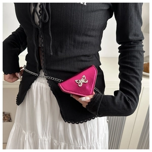 Gros plan sur le sac triangle fuchsia métallisé avec un ornement papillon argenté