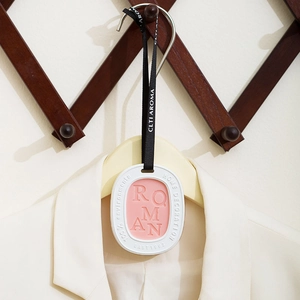 Pink and white oval aromatic wax tablet hanging on a hanger for wardrobe scent
