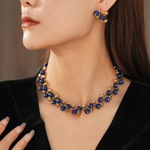 Detail of vintage flower jewelry set with blue beads and gold finish on a model