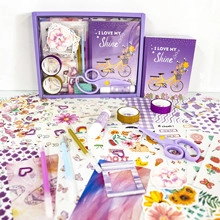 Flat lay detail of purple DIY mermaid journal kit with notebook, stickers, and washi tapes