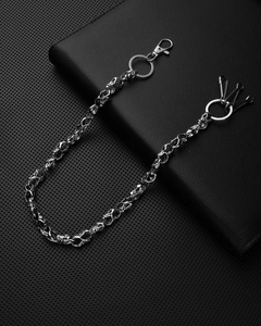 Close-up of a silver skull metal trousers chain with lobster clasps on black leather