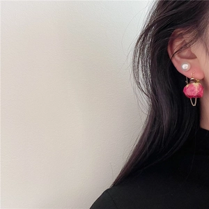 Detail of elegant red rose bud earrings with pearl and gold chain on model's side profile