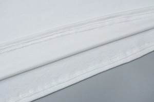 Détail de l'ourlet d'une robe blanche en coton montrant la couture à double aiguille