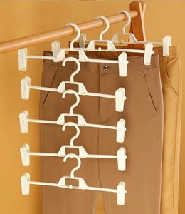 Space-saving white plastic pant hangers with adjustable clips in a vertical multi-tier stack