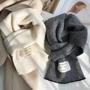 Détail d'écharpes en maille blanc crème et pied-de-poule avec étiquettes tissées